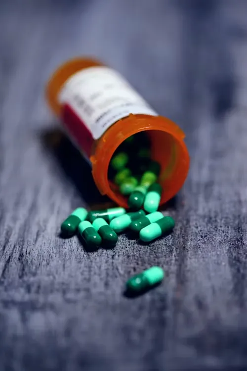 Green capsules spilling from a medicine bottle