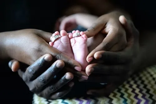 Parents cradling their newborn baby's feet in their hands
