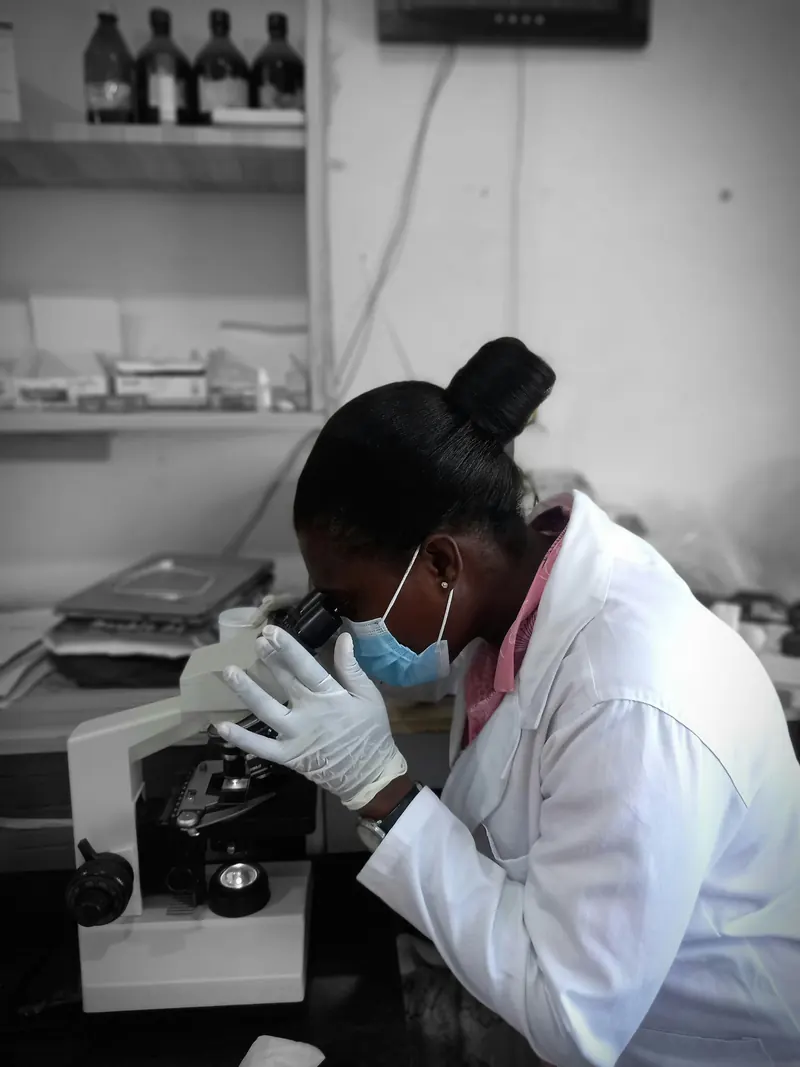A scientist in a lab coat examining a sample under a microscope